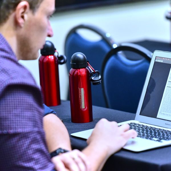 Participante faz anotações no notebook durante uma aula