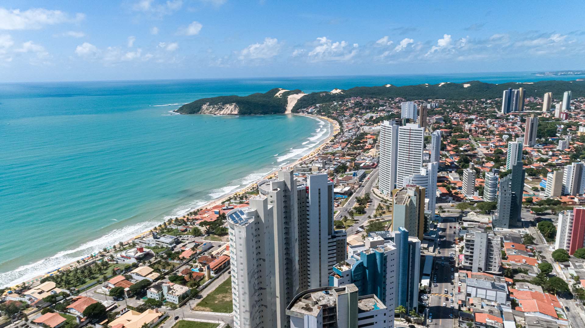 Vista aérea da praia de Ponta Negra, em Natal, com o Morro do Careca, o mar e os prédios da orla