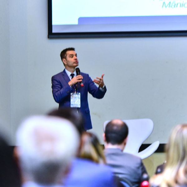 Palestrante fala ao microfone para a plateia de um evento