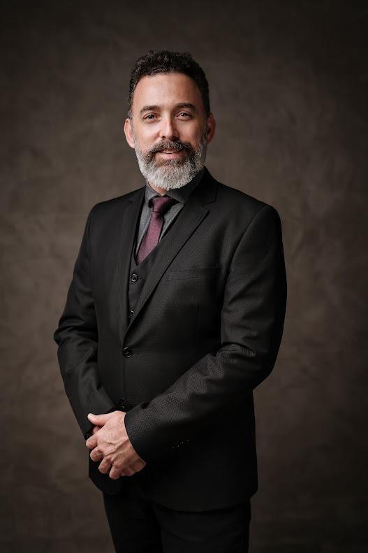 Professor Ronaldo Corrêa, de terno escuro e gravata vinho, em retrato de estúdio